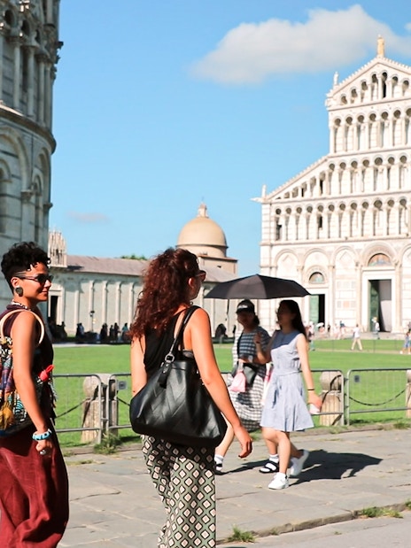 Tourists walking near Pisa Cathedral on a guided tour from Florence.