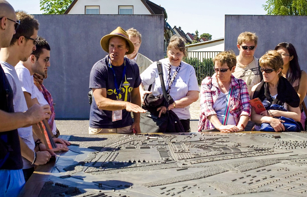Visitors at Sachsenhausen Concentration Camp Memorial with guide, exploring historical site in Oranienburg, Germany.