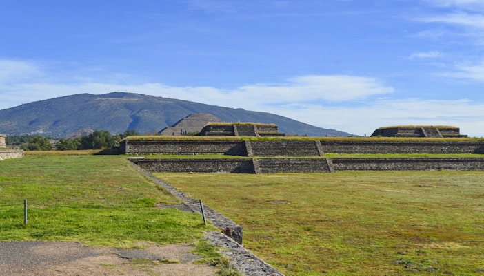 Ancient pyramids at La Ciudadela de Teotihuacan with mountain backdrop.