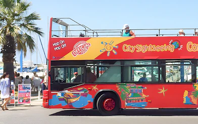 Red double-decker bus for Benalmádena hop-on hop-off tour near marina.