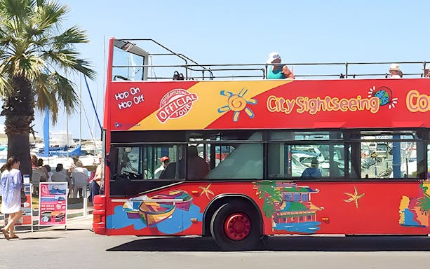 Red double-decker bus for Benalmádena hop-on hop-off tour near marina.