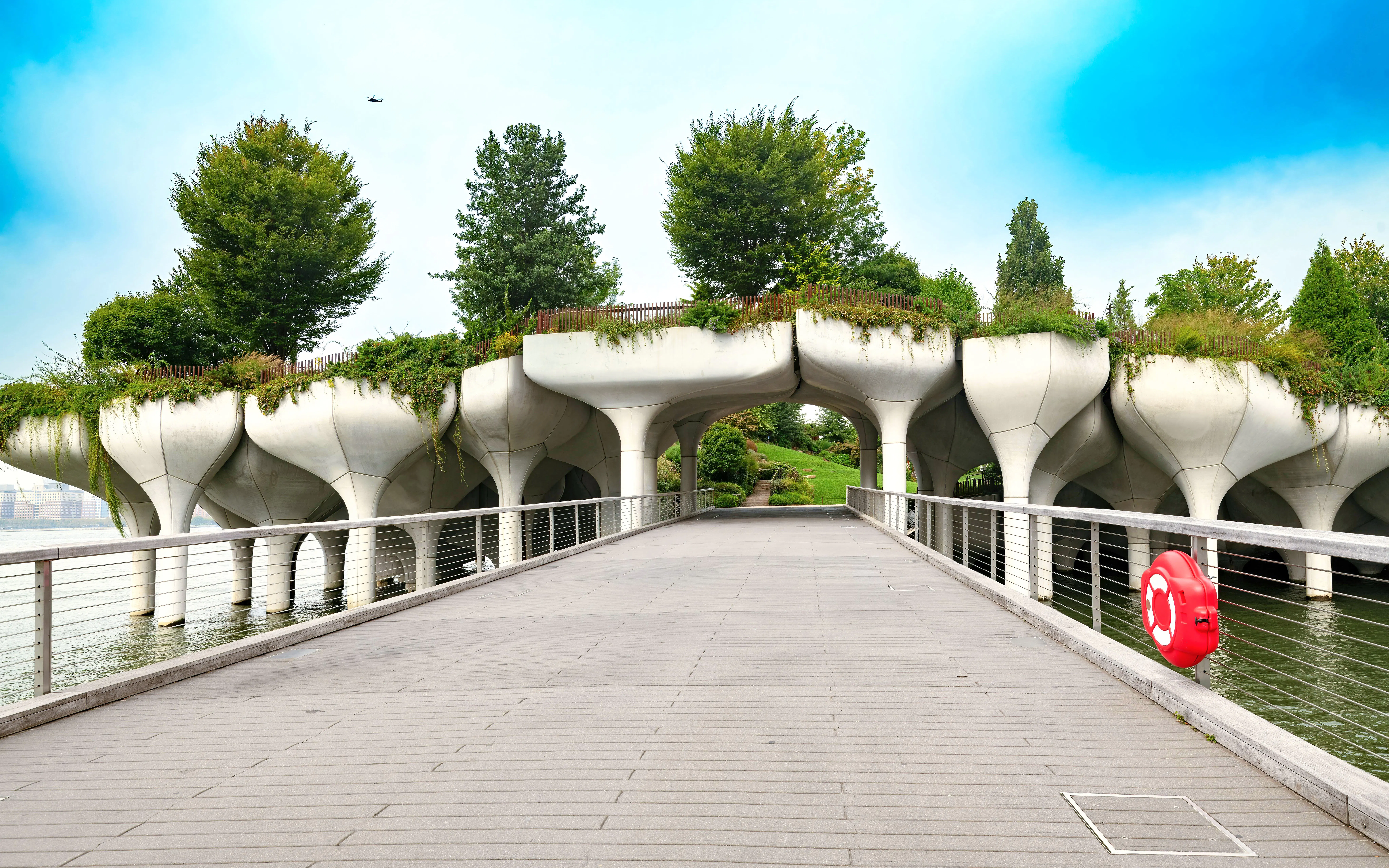 Bridge to Little Island at Pier 55, Chelsea, New York City, with unique concrete pillars and greenery.