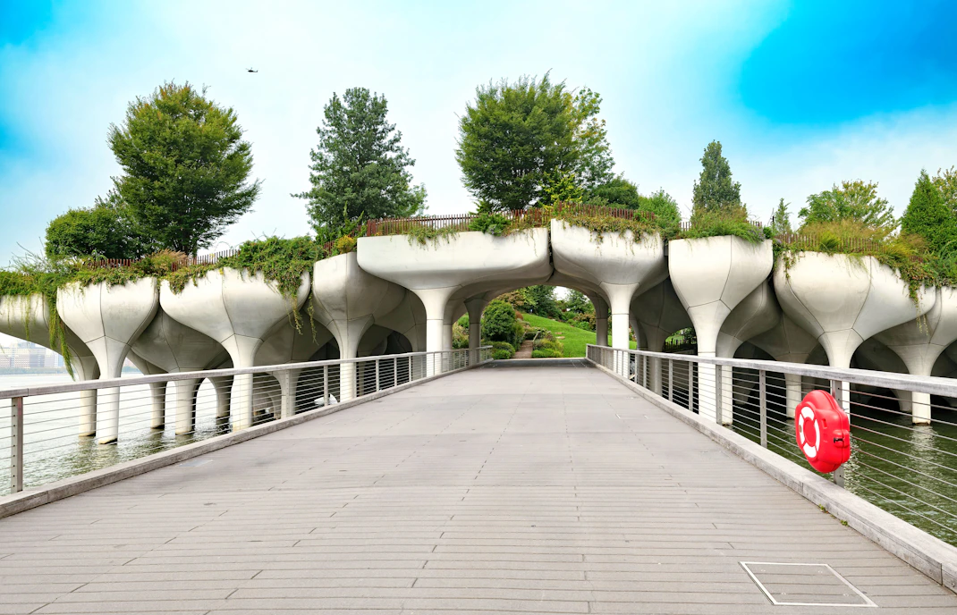 Bridge to Little Island at Pier 55, Chelsea, New York City, with unique concrete pillars and greenery.