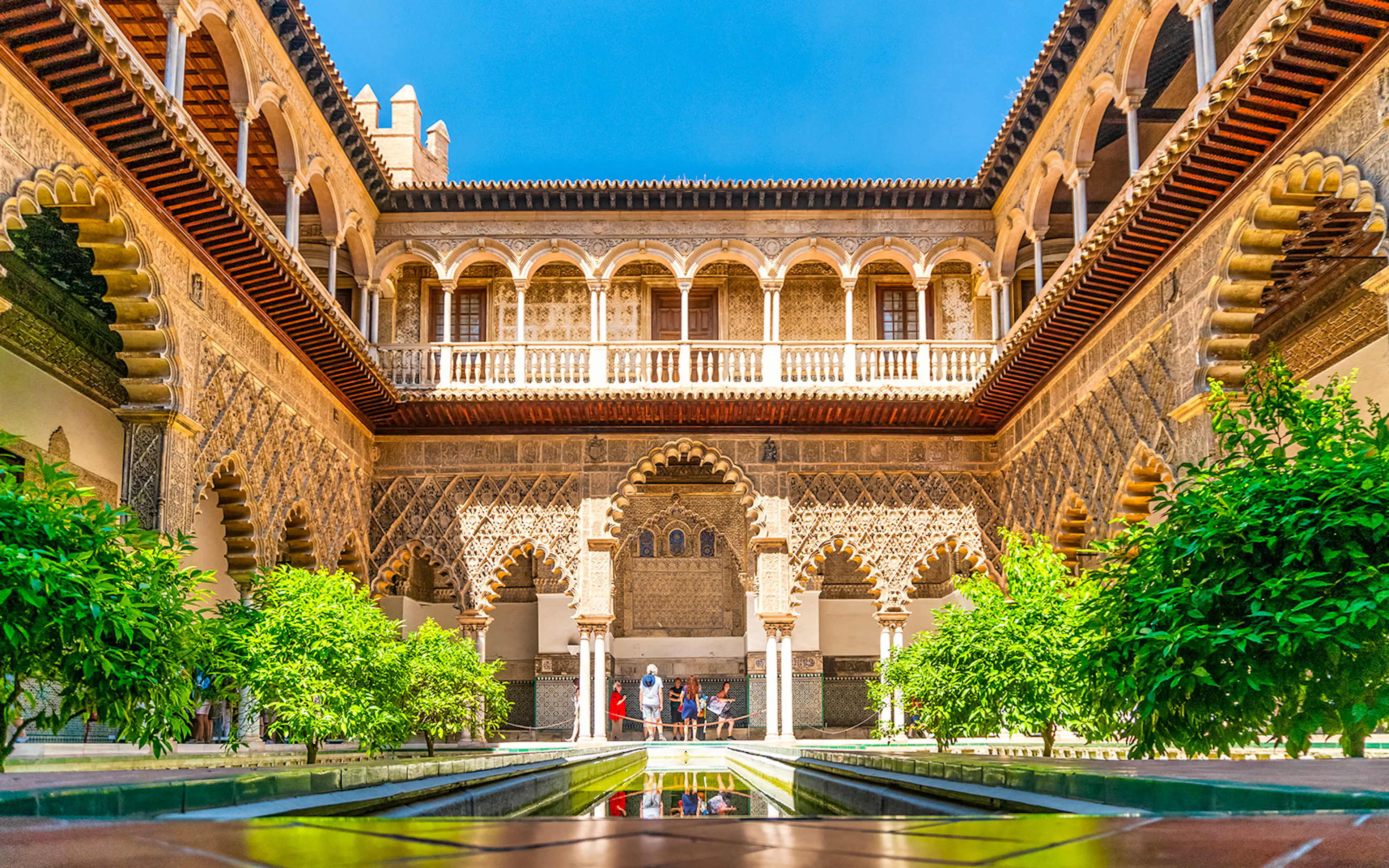 Tour guide leading group through Alcazar of Seville, highlighting Moorish architecture.