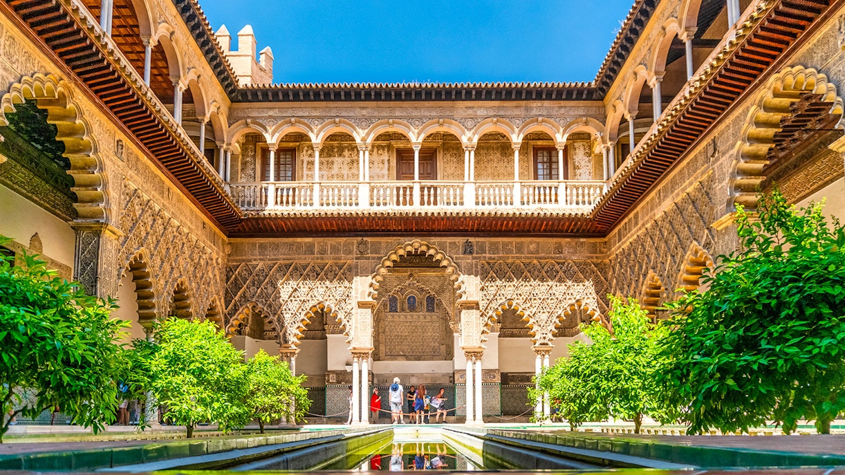 Tour guide leading group through Alcazar of Seville, highlighting Moorish architecture.