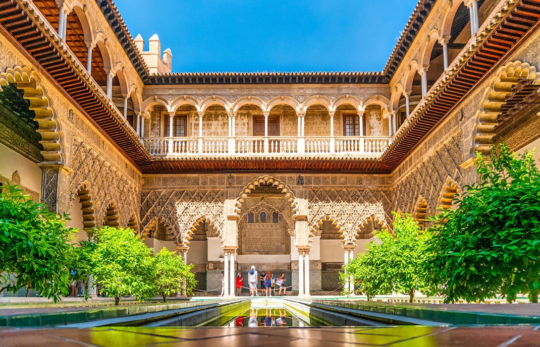 Tour guide leading group through Alcazar of Seville, highlighting Moorish architecture.
