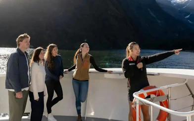 Tour guide pointing out sights to a small group on Milford Sound cruise from Te Anau.