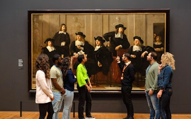Visitors viewing a large painting at the Rijksmuseum in Amsterdam.