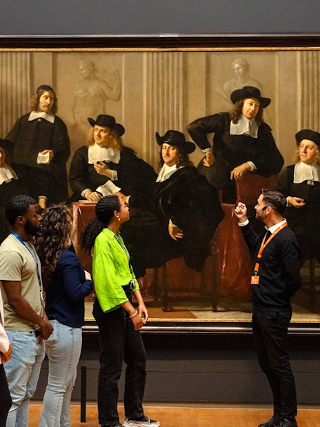 Visitors viewing a large painting at the Rijksmuseum in Amsterdam.