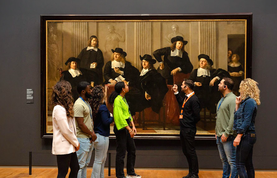 Visitors viewing a large painting at the Rijksmuseum in Amsterdam.