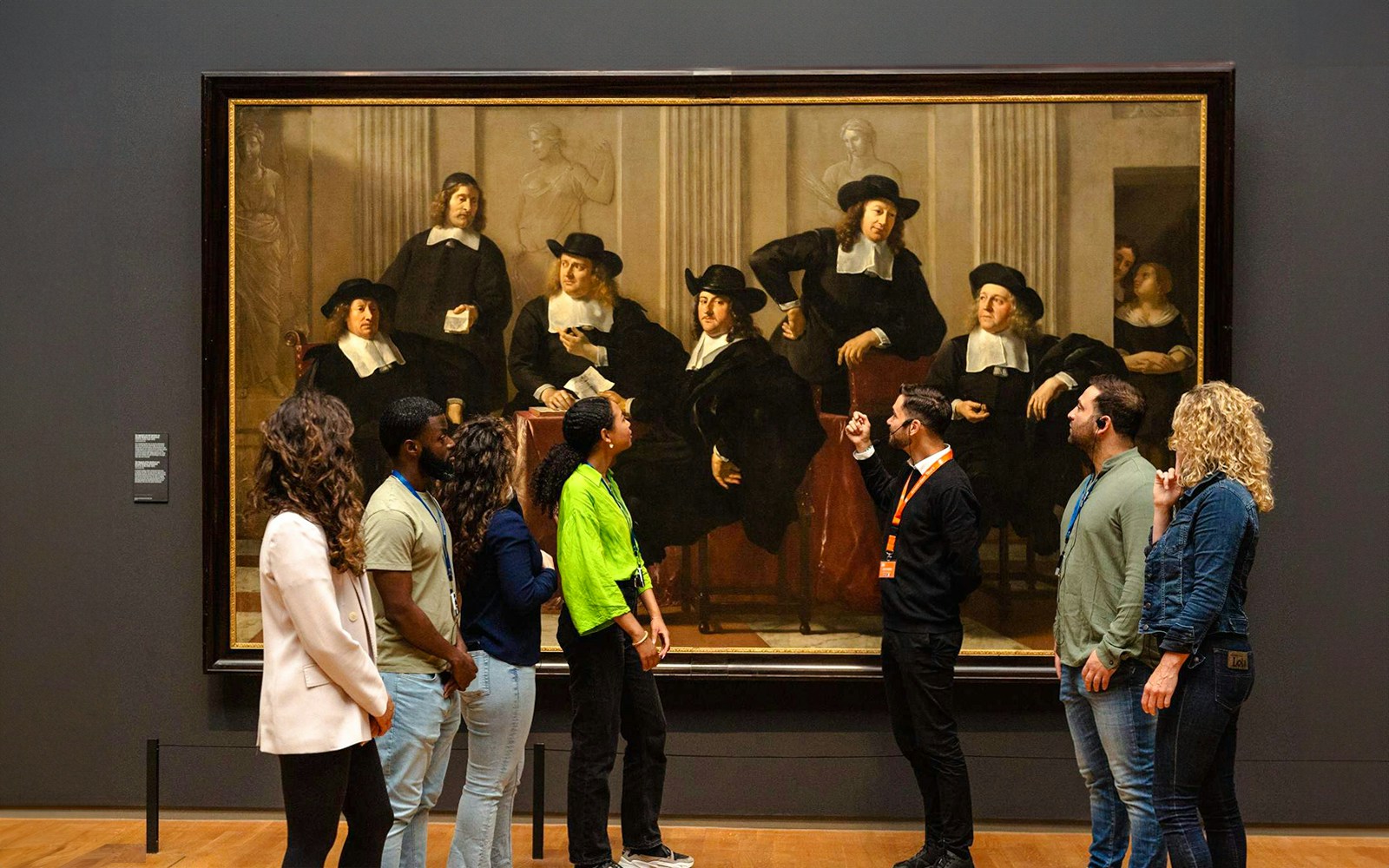 Visitors viewing a large painting at the Rijksmuseum in Amsterdam.