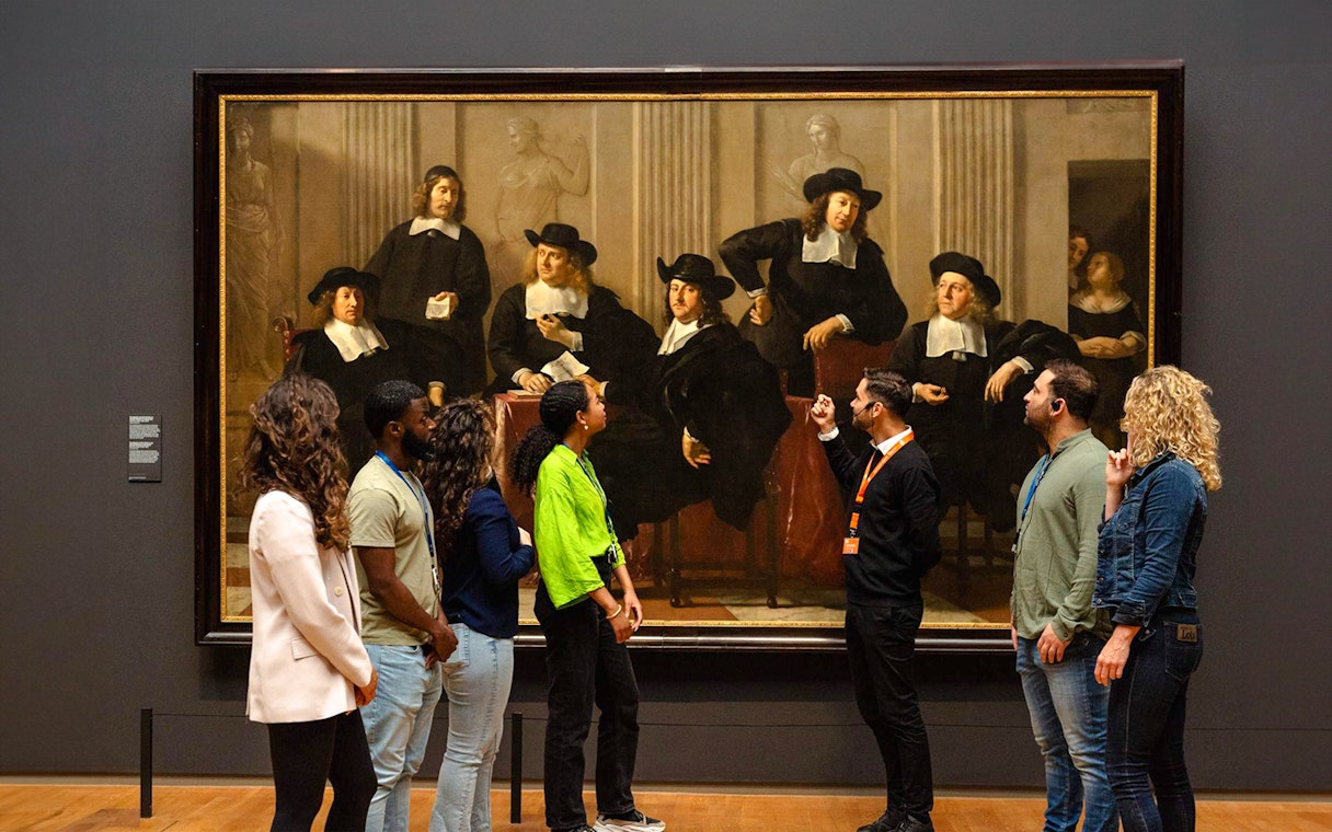 Visitors viewing a large painting at the Rijksmuseum in Amsterdam.