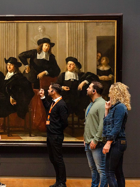 Visitors viewing a large painting at the Rijksmuseum in Amsterdam.