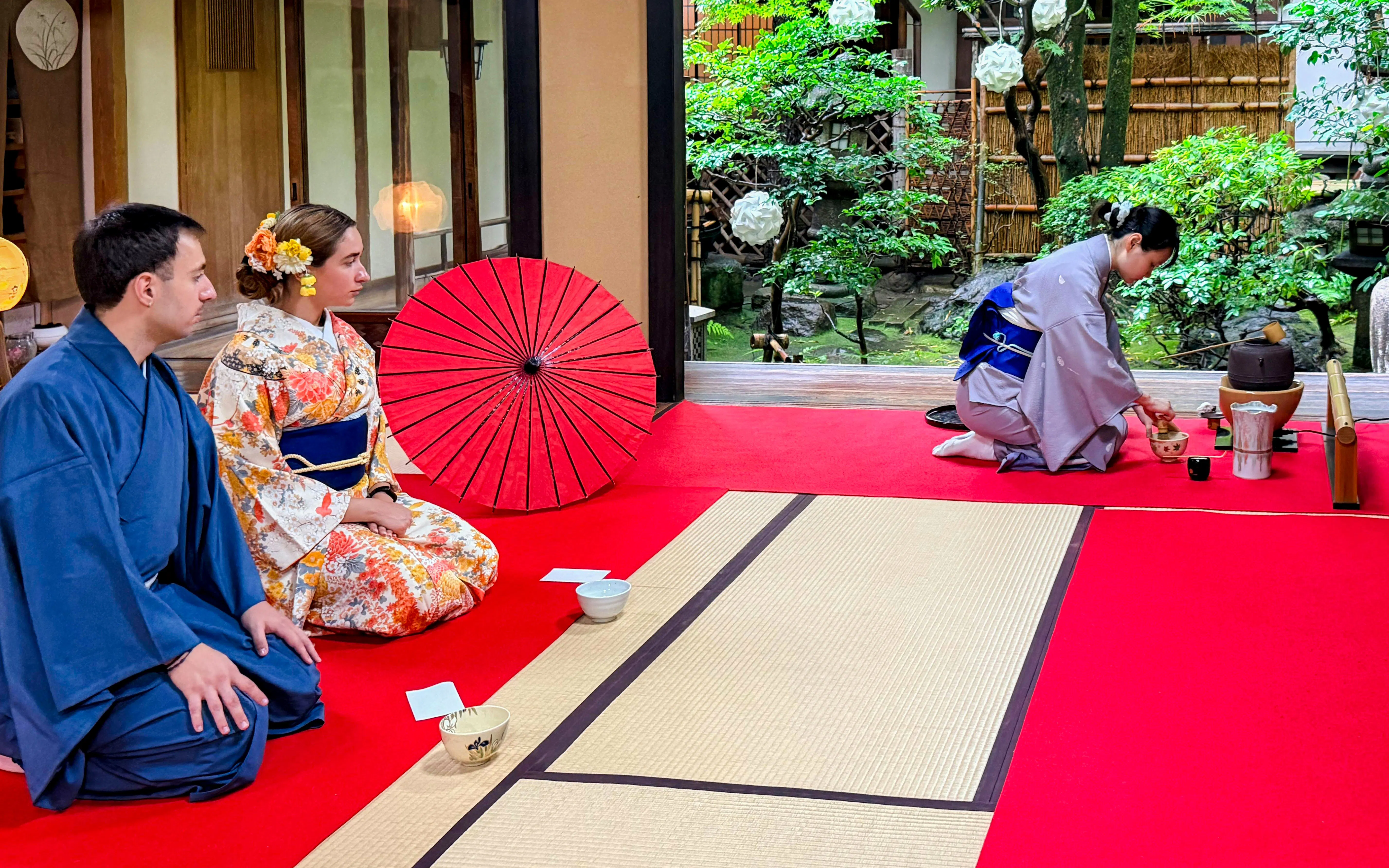 Participants in kimonos attending a Japanese tea ceremony in a traditional setting.