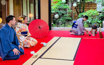Participants in kimonos attending a Japanese tea ceremony in a traditional setting.