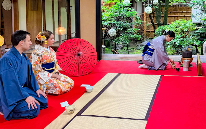 Participants in kimonos attending a Japanese tea ceremony in a traditional setting.