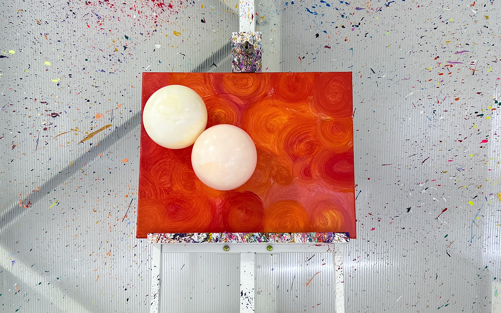 Balloon splatter art on canvas with vibrant orange swirls at workshop.