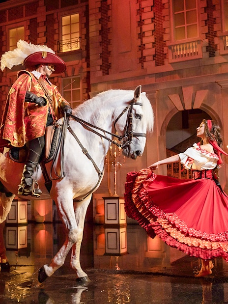 Performer on horseback and dancer in costume at Puy du Fou Theme Park show.