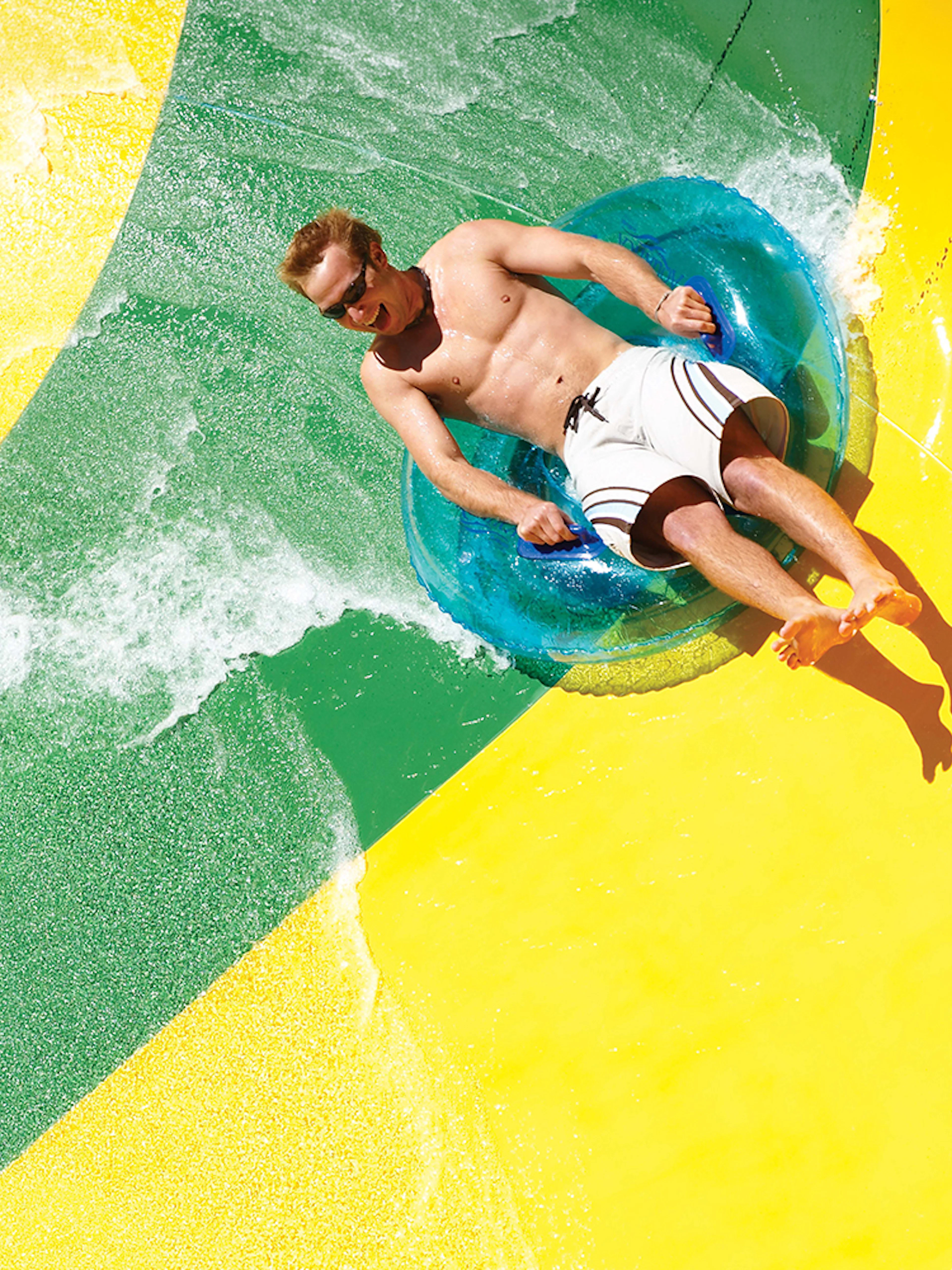 Man on a tube sliding down a waterslide at Aquatica San Antonio, Texas.