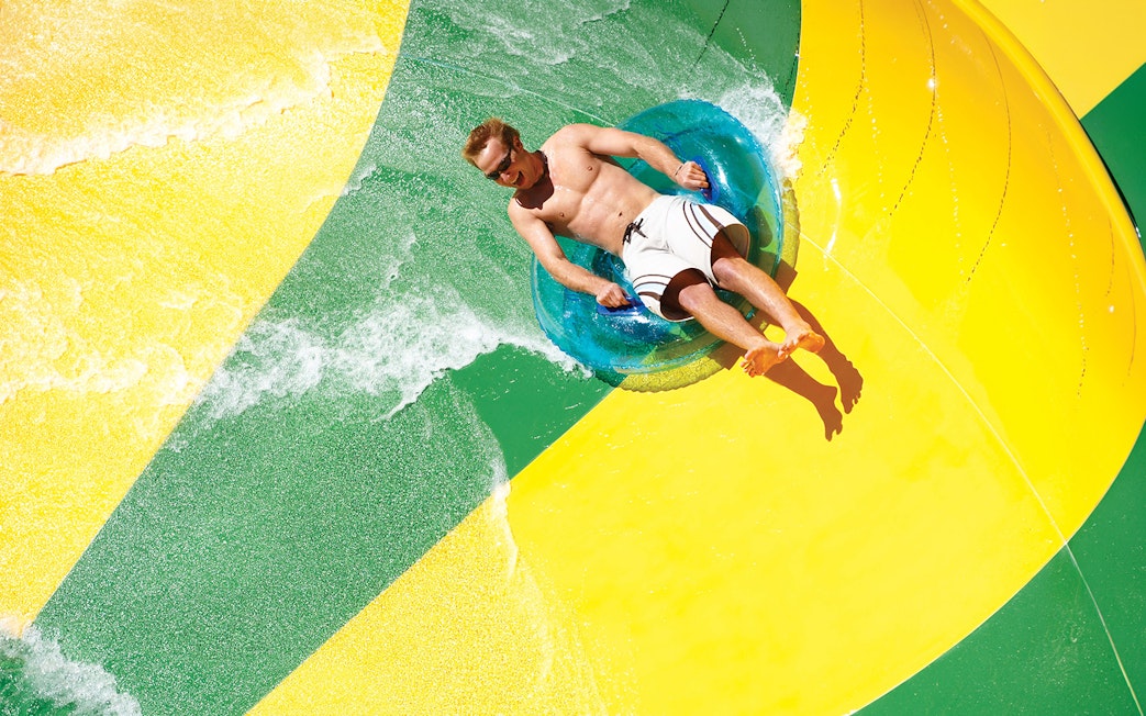 Man on a tube sliding down a waterslide at Aquatica San Antonio, Texas.