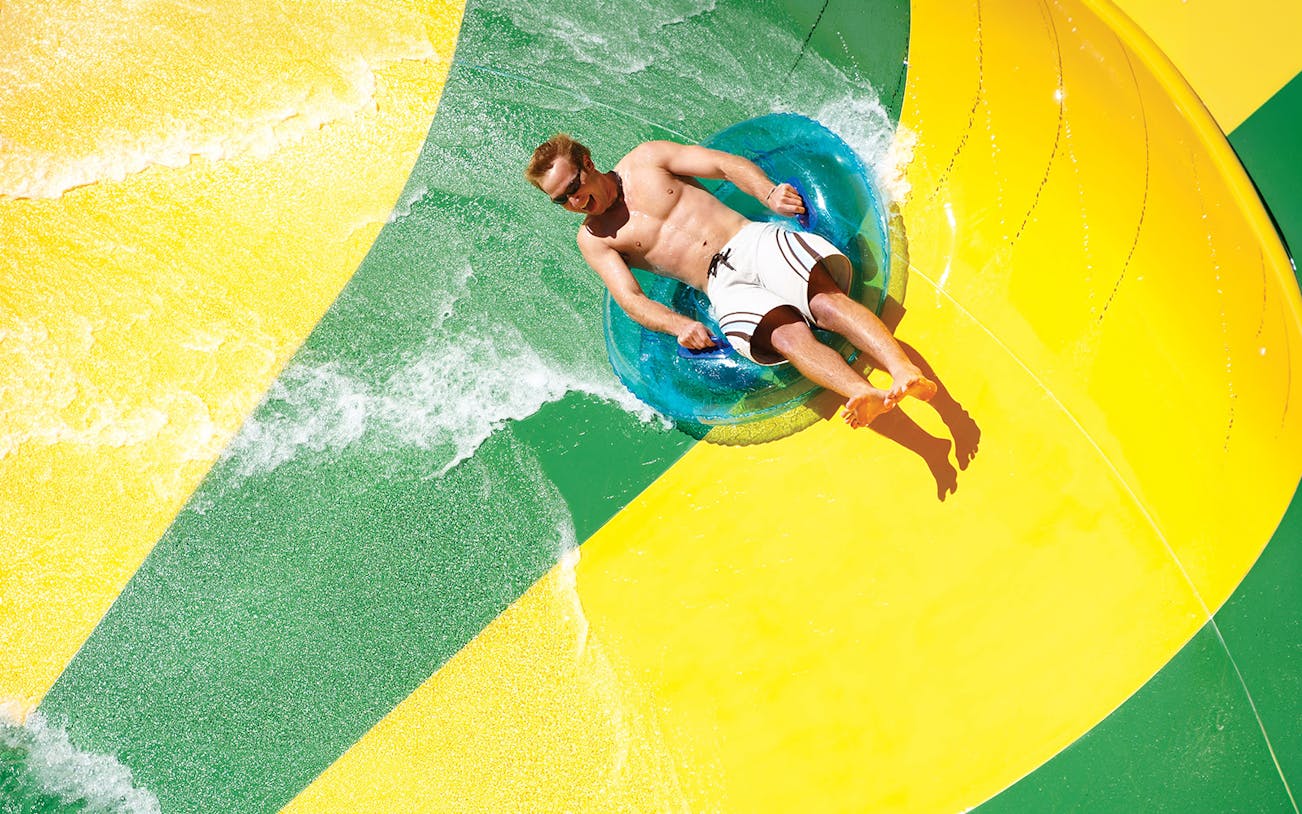 Man on a tube sliding down a waterslide at Aquatica San Antonio, Texas.