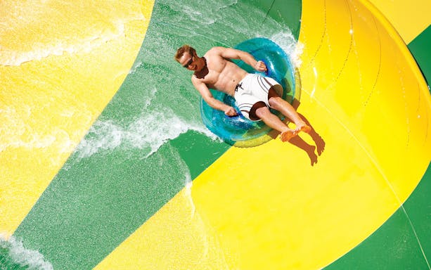 Man on a tube sliding down a waterslide at Aquatica San Antonio, Texas.