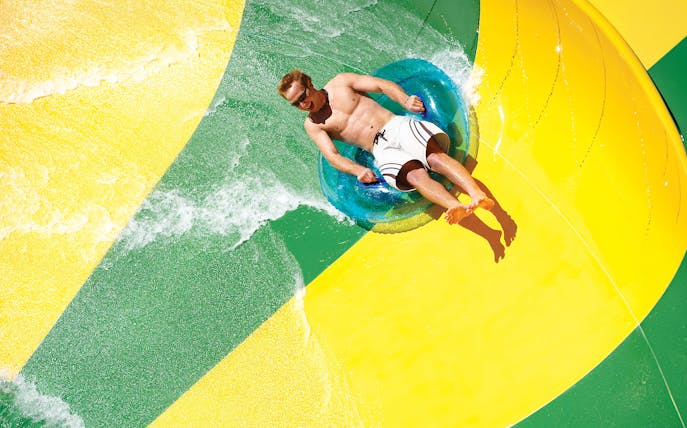 Man on a tube sliding down a waterslide at Aquatica San Antonio, Texas.