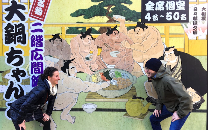 Visitors posing with sumo mural at Ryogoku, Tokyo during morning practice tour.
