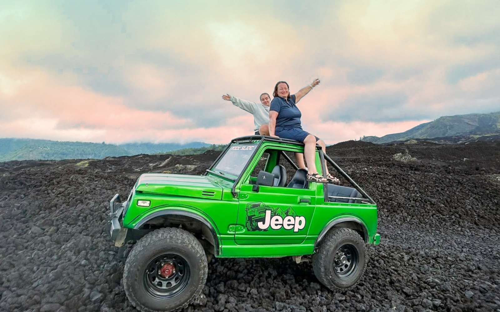 Tourists on a green Jeep during Mount Batur sunrise tour, Bali.