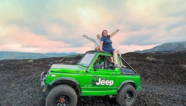 Tourists on a green Jeep during Mount Batur sunrise tour, Bali.