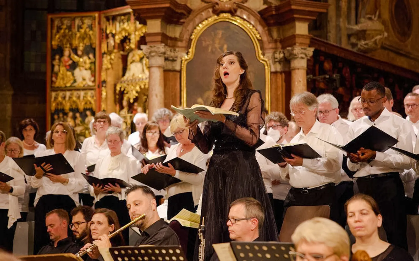 Orchestra and choir performing inside St. Stephen's Cathedral, Vienna, with audience seated.