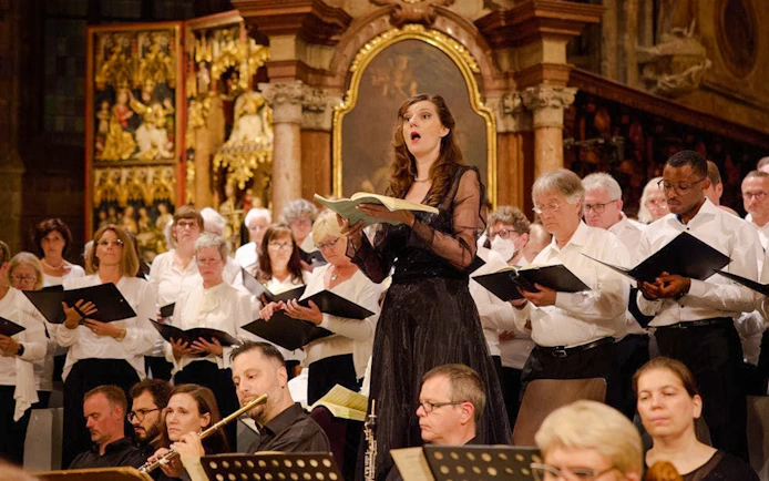 Orchestra and choir performing inside St. Stephen's Cathedral, Vienna, with audience seated.