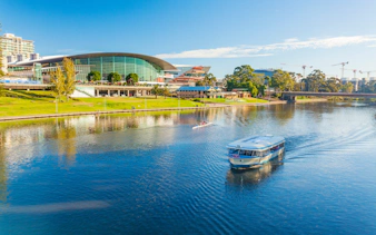 River cruise boat on Adelaide River with cityscape in the background.