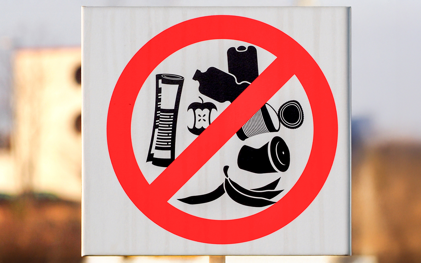 No littering sign in desert area with crossed-out trash symbols.