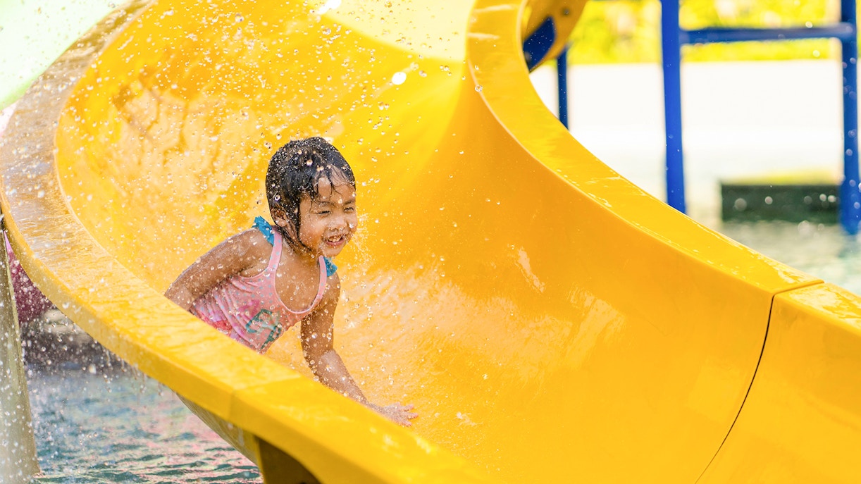 Child enjoying a yellow water slide at Aqualeon Water Park, Tarragona.
