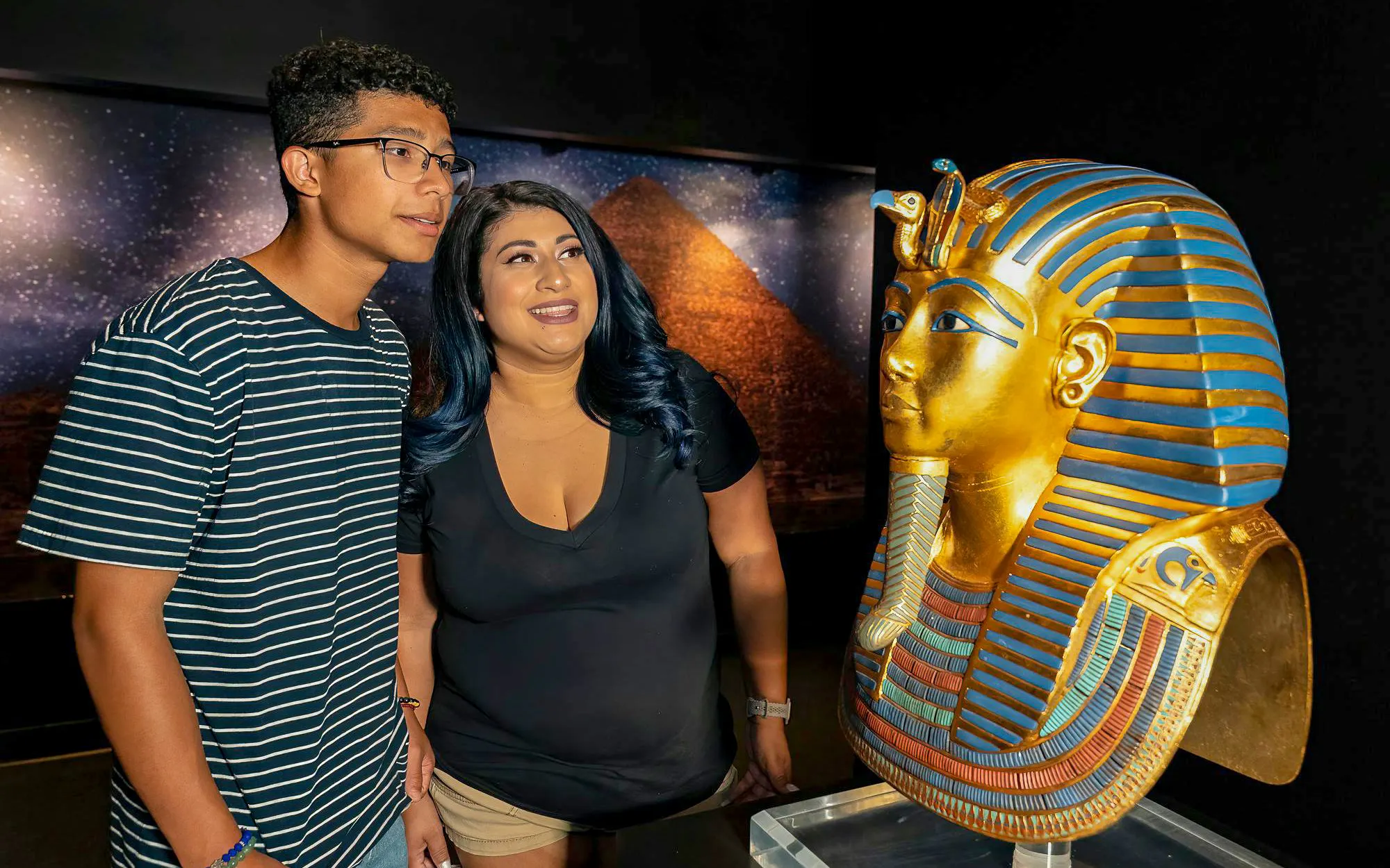 Visitors admiring King Tutankhamun's golden mask exhibit.
