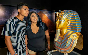 Visitors admiring King Tutankhamun's golden mask exhibit.