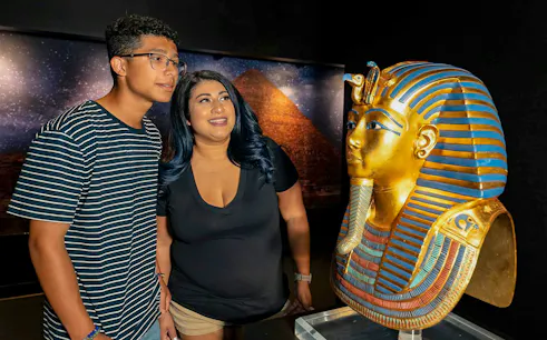 Visitors admiring King Tutankhamun's golden mask exhibit.