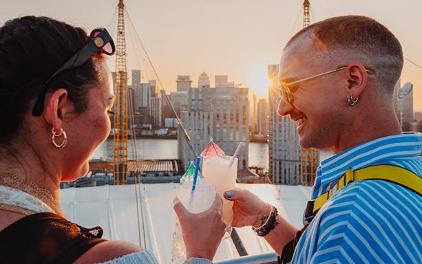 Guests enjoying drinks atop the O2 with a cityscape view at sunset.