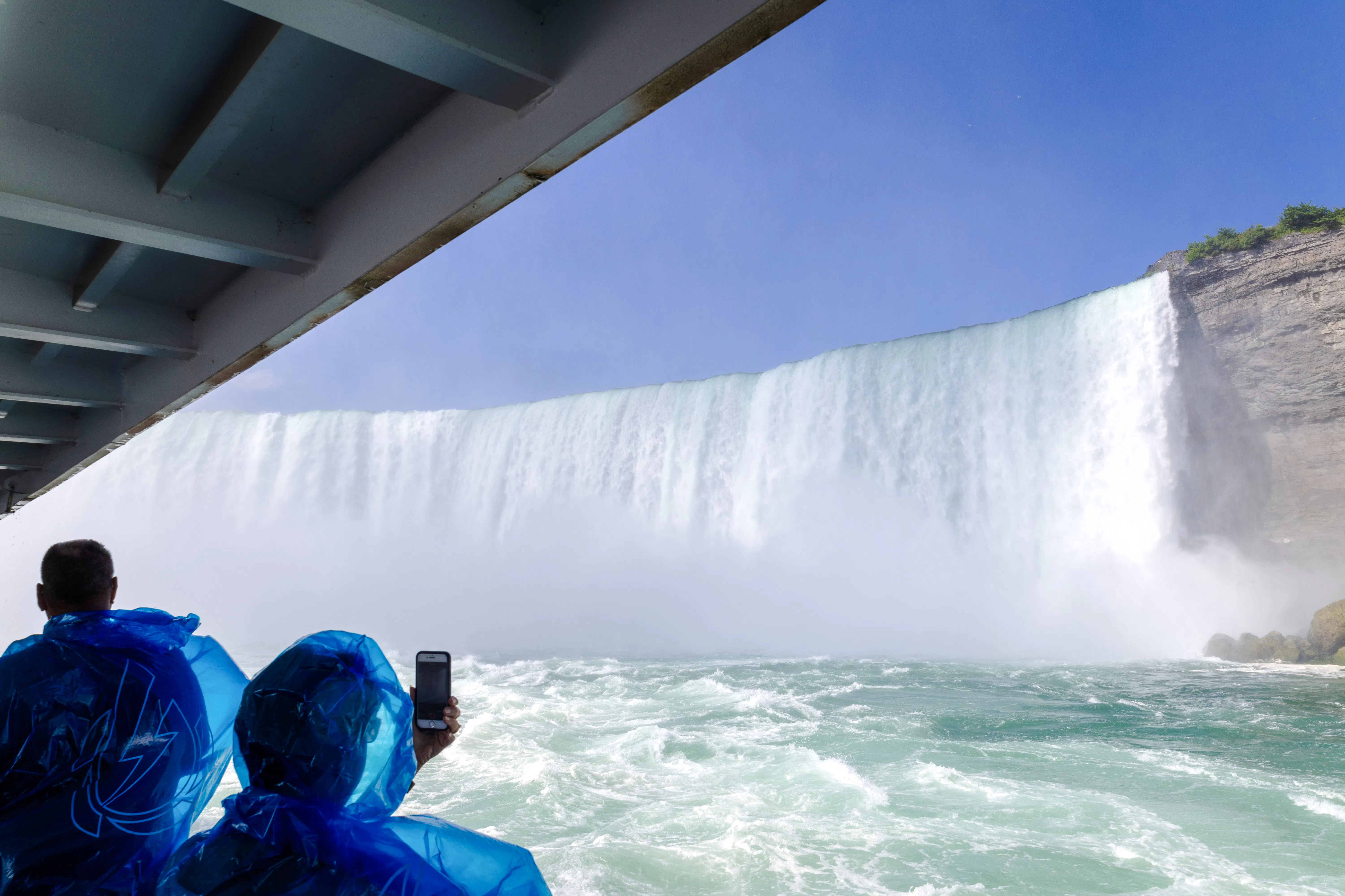 Visitors in blue ponchos on a boat tour near Niagara Falls, USA.