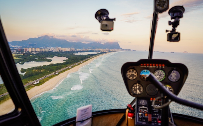 Helicopter cockpit view over Rio de Janeiro coastline and cityscape.