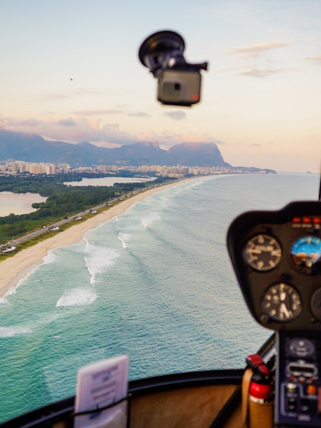 Helicopter cockpit view over Rio de Janeiro coastline and cityscape.