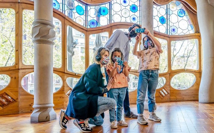 Family exploring Casa Batlló interior with stained glass windows, Barcelona.
