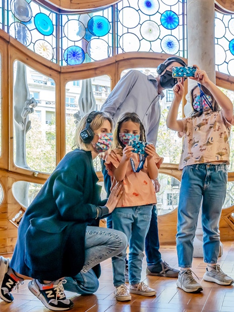 Family exploring Casa Batlló interior with stained glass windows, Barcelona.