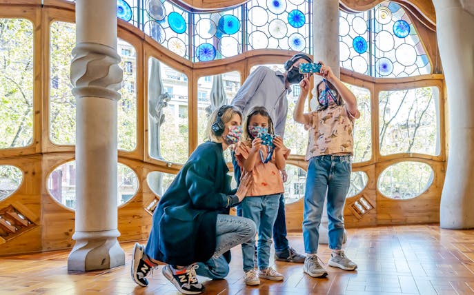 Family exploring Casa Batlló interior with stained glass windows, Barcelona.