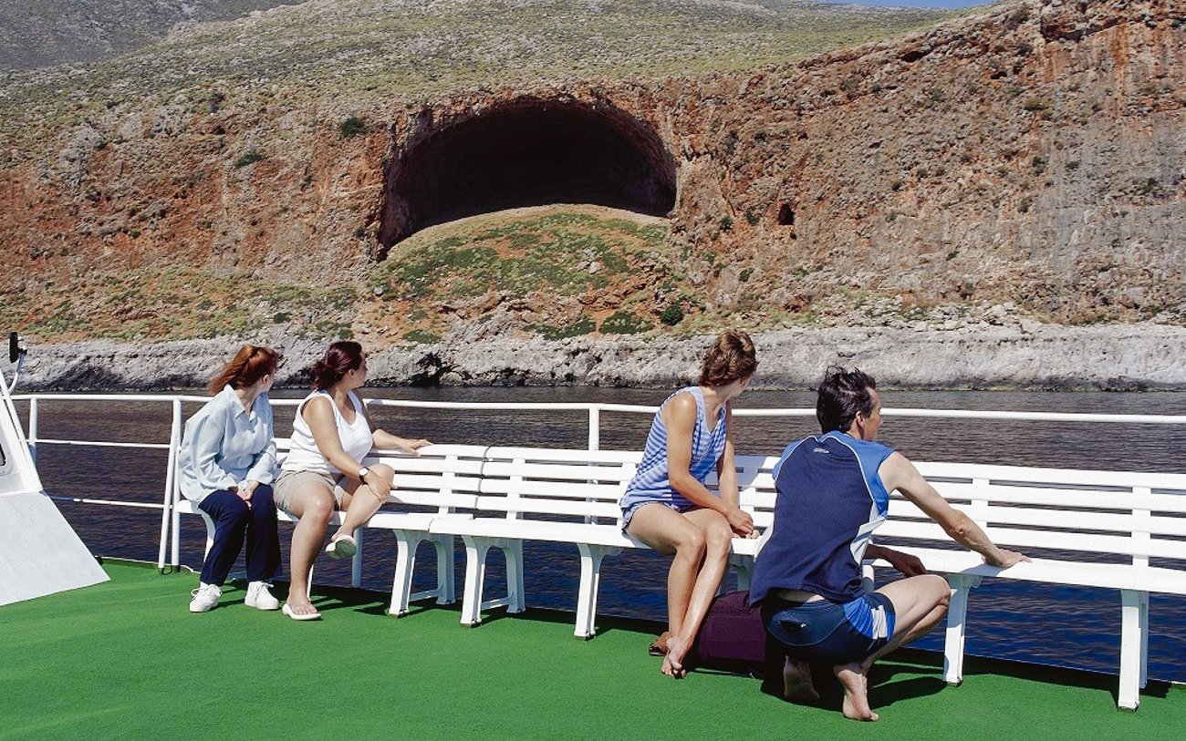 Guests on boat cruise viewing rocky landscape at Balos Lagoon, Greece.