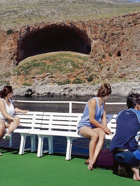 Guests on boat cruise viewing rocky landscape at Balos Lagoon, Greece.