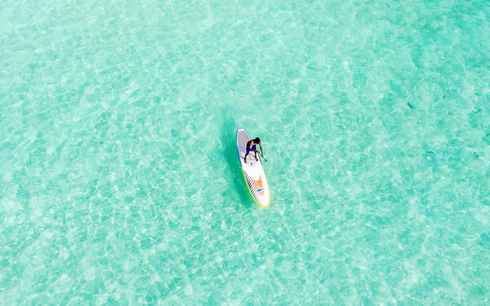 Man paddleboarding on clear water at Moreton Island.