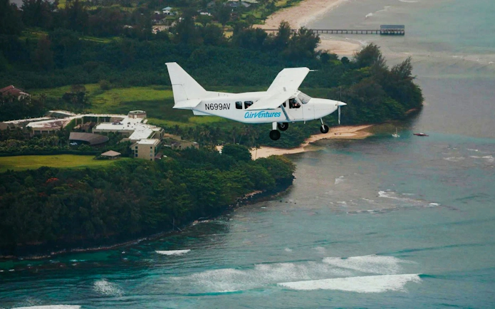 Small plane flying over Kauai coastline during private air tour.