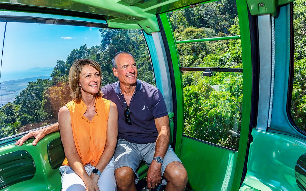 Couple enjoying the view from Kuranda Skyrail Cableway over lush rainforest and coastline.